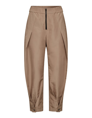 Co Couture Trice Pleat Pant sand: Tanfarbene Hose mit elastischem Bund, Reißverschluss, Falten entlang der Beine und Druckknopfverschlüssen an den Knöcheln, die eine moderne, cleane Silhouette betont.