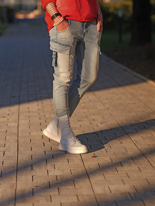Person trägt OFF#DLY Denim Verona blue, eine lässige, hellblaue Cargo-Jeans mit umgeschlagenem Saum. Sichtbare Taschen und leichte Waschungen sorgen für urbanen Look, kombiniert mit weißen Stiefeln.