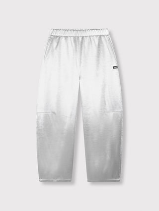 ALIX Woven Shiny Pant silver: Locker geschnittene, metallic-silberne Jogginghose mit elastischem Bund, leicht konisch zulaufenden Beinen, seitlichen Eingrifftaschen und kleinem schwarzen Label auf einem Oberschenkel.