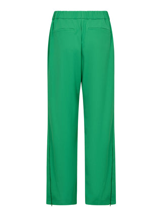 Co Couture Amina Zip Panel Pant grün: Rückansicht von leuchtend grünen Hosen mit elastischem Bund, zwei Paspeltaschen, geradem, lockerem Bein und kleinen Reißverschlüssen am Saum.