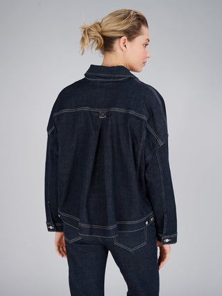 Rückansicht einer Frau mit lockerem Dutt, die die True Religion Amber Jacket Raw Denimjacke trägt, mit markanten Kontrastnähten und lässigem Oversize-Schnitt, kombiniert mit passenden Jeans.