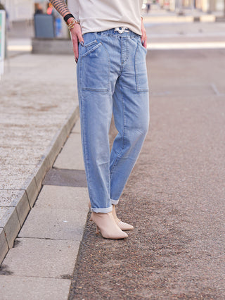 Person trägt OFF#DLY Joggpant Stella blue mit großen Fronttaschen und hochgekrempelten Säumen, kombiniert mit nudefarbenen Stiefeletten. Ein lockerer, moderner Look, der Komfort und Stil vereint.