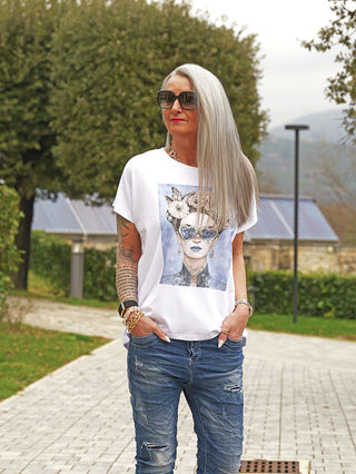 Frau trägt das OFF#DLY Tee F.Karlo mit auffälligem Frontprint einer Frau mit herzförmiger Brille. Das Oversize-T-Shirt fällt lässig, kombiniert mit leicht zerstörten Jeans.