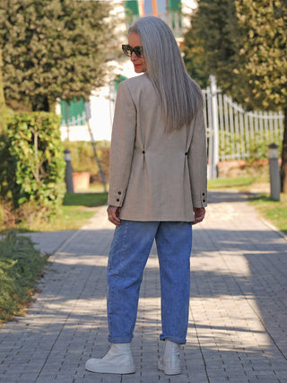 Person von hinten in einem Mava Power Blazer bone, kombiniert mit blauen Jeans und weißen Stiefeletten. Der Blazer zeigt eine klare Linienführung und elegante Details für einen stilvollen Look.