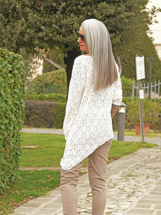 Person von hinten in einem asymmetrischen, weißen OFF#DLY Longshirt Spitze Tina, mit elegantem, fließendem Schnitt, auf einem Gartenpfad stehend.