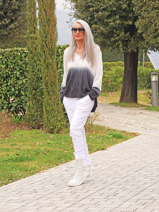 Frau mit grauem Haar trägt den OFF#DLY Pulli Tortona black/white, dessen Farbverlauf von Grau zu Weiß und lockerem Schnitt modern und lässig wirkt.