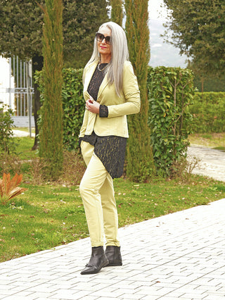 Eine Frau trägt den OFF#DLY Blazer Britt matcha, einen schmal geschnittenen, eleganten Blazer mit klassischem Reverskragen, kombiniert mit passenden schlanken Hosen und schwarzen Stiefeletten.