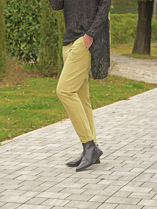 Person trägt OFF#DLY Pant Cleo matcha, moderne, schmal geschnittene Hose in hellgrünem Ton, kombiniert mit schwarzen spitzen Ankle-Boots. Perfekt für stilvolle Alltags- und Business-Looks.