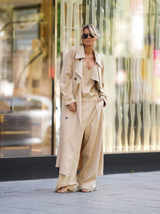 Frau in beigeem Outfit trägt Gitta Banko Kasandra Pant camel, weite Hose mit fließender Silhouette, kombiniert mit Trenchcoat, Camisole und Accessoires, ideal für stilvolle Street-Style-Looks.