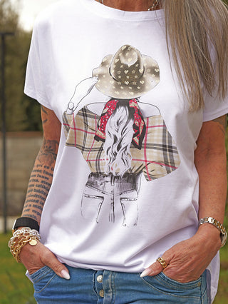 Person trägt das OFF#DLY Tee Hat red mit einem auffälligen Frontprint einer Frau im Cowboy-Stil, kombiniert mit lässigen blauen Jeans. Accessoires: goldene Armreifen und schwarze Armbänder.