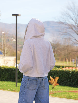 Person von hinten in OFF#DLY Sweatjacke KISS lightgrey, lässiger Schnitt, Kapuze mit Kordelzug, markanter Mundform-Reißverschluss, kombiniert mit blauen Jeans, ideal für entspannte Alltagslooks.