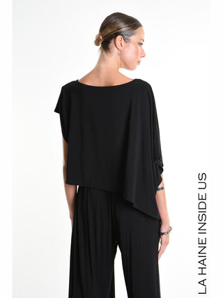 La Haine Tee 5269 black: Rückenansicht einer Frau in asymmetrischem Crop-Shirt aus weichem Bamboo-Jersey mit weiten Kimono-Ärmeln, präsentiert die avantgardistische Silhouette des italienischen Labels La Haine Inside Us.