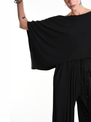 La Haine Tee 5269 black: Modell trägt ein weites, asymmetrisches Crop-Shirt mit Kimono-Ärmeln aus Bamboo-Jersey, kombiniert mit lockeren Hosen, zeigt Schmuck und LA HAINE INSIDE US-Schriftzug am Bein.