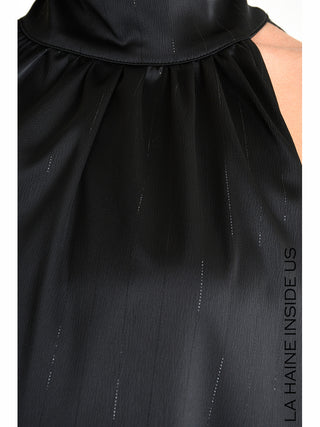 La Haine Dress 5285 black: Nahaufnahme eines schwarzen, ärmellosen Oberteils mit hochgeschlossenem Kragen und gefaltetem Ausschnitt aus leicht strukturiertem, seidigem Stoff. Text LA HAINE INSIDE US am Bildrand.