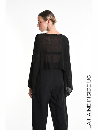 La Haine Shirt 5371 black von hinten gezeigt, ein locker fallender, halbtransparenter schwarzer Strickpullover mit weiten Oversize-Ärmeln und verkürztem Schnitt, kombiniert mit weit geschnittenen, hoch taillierten schwarzen Hosen.