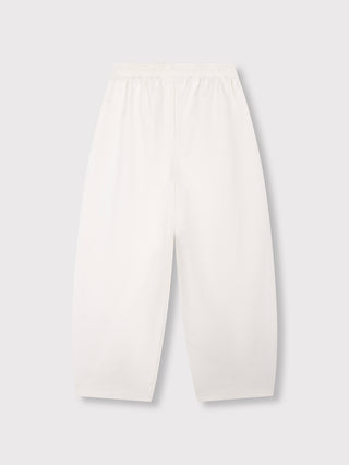 ALIX Baloon Sweat Pant cream: Weite, weiße Hose mit elastischem Bund und leicht verjüngtem Schnitt aus weichem, opakem Material. Geprägtes ALIX Logo auf der Vorderseite betont den sportlich-eleganten Look.