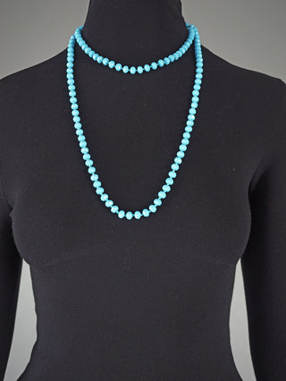 Ein schwarzer Dressform trägt eine zweisträngige Glasperlenkette oval 7 mm türkis; ein Strang als Choker, der andere hängt länger und erreicht eine Gesamtlänge von 58 cm.