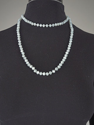 Die Glasperlenkette oval 7 mm silber präsentiert sich auf einer schwarzen Büste. Zwei Stränge kleiner, facettierter, blassgrauer Perlen, einer als Choker, der andere tiefer fallend.