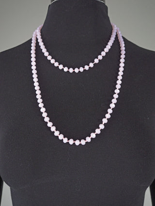 Glasperlenkette oval 7 mm rosa, präsentiert auf einer schwarzen Schneiderpuppe. Die Kette aus blassrosa, facettierten Perlen hängt in zwei Schleifen, ideal für vielseitige Tragemöglichkeiten.