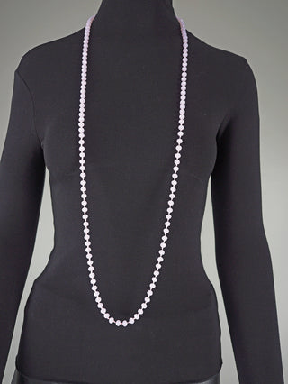 Eine schwarze Schaufensterpuppe trägt ein langes, facettiertes, rosafarbenes Glasperlenkette oval 7 mm rosa, das elegant über die Taille hinausragt.