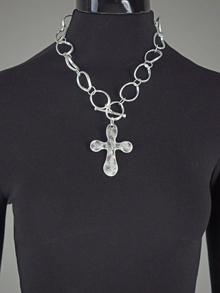 OFF#DLY Kreuzcollier silber: Ein kräftiges, silbernes Halsband mit unregelmäßigen, ovalen Gliedern und einem grob strukturierten Kreuzanhänger. Präsentiert auf einem schwarz gekleideten Mannequin mit einem Knebelverschluss.