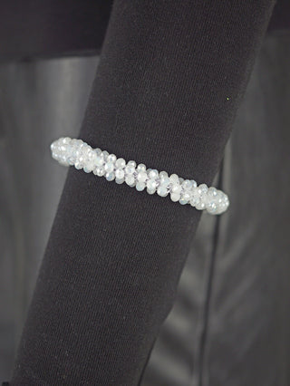 Das OFF#DLY Perlarmband weiß ist ein facettiertes Glasarmband mit milchig-weißem Schimmer, präsentiert auf einem schwarzen, stoffbezogenen Display, mit elastischem Verschluss.