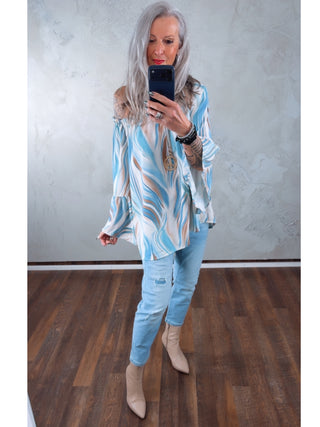 Ältere Frau trägt OFF#DLY Denim Milano lightblue, eine leicht zerstörte Skinny-Jeans mit modernem Used-Look, kombiniert mit einer langärmligen Bluse und nudefarbenen Stiefeletten.