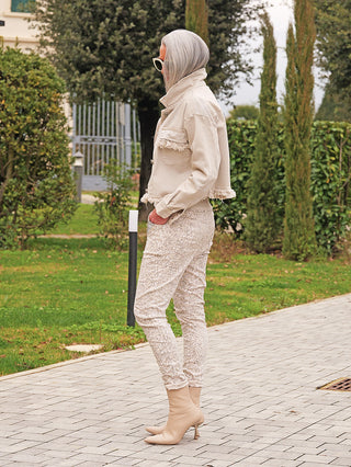 Person mit schulterlangem grauem Haar trägt die OFF#DLY Denimjacke Dana beige mit Fransen. Die kurze Jacke und das stylische Design betonen einen lässigen, modernen Look.