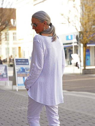 Frau von hinten, trägt das OFF#DLY Shirt Eva white: ein locker sitzendes, langärmliges Oberteil mit Rundhalsausschnitt und Oversized-Look, perfekt kombiniert mit einer weißen Hose.