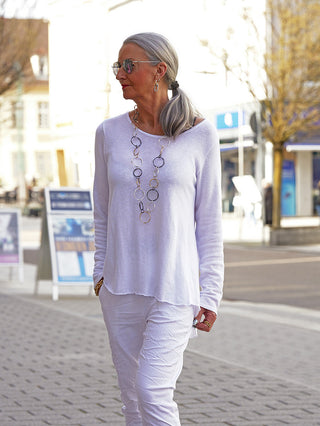 Eine stilvolle Frau trägt das OFF#DLY Shirt Eva white, ein locker sitzendes, oversized weißes Oberteil mit 3/4-Ärmeln, ideal für vielseitige Looks in urbaner Umgebung.
