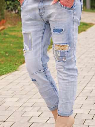 OFF#DLYDenim Destroy Camo lightblue Jeans mit auffälligem Destroyed-Look, Camouflage- und Glitzer-Patches, getragen mit leicht hochgekrempelten Beinen und kombiniert mit nude-beigen Ankle Boots.