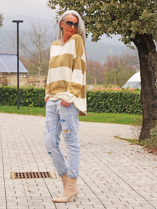 Person trägt den OFF#DLY Pulli Ancona beige/khaki mit weitem Schnitt und breiten Streifen, kombiniert mit lässigen Jeans und beigen Stiefeletten, ideal für entspannten, stilvollen Look.