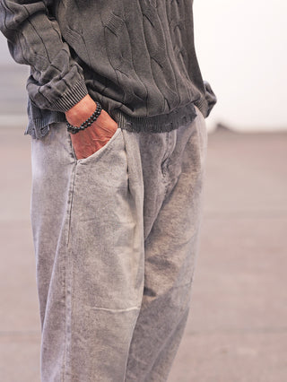 Person trägt die OFF#DLY Denim Venedig grey, eine locker geschnittene, leicht verwaschene Jeans mit elastischem Gummibund hinten und seitlichen Taschen, kombiniert mit einem grauen Strickpullover.