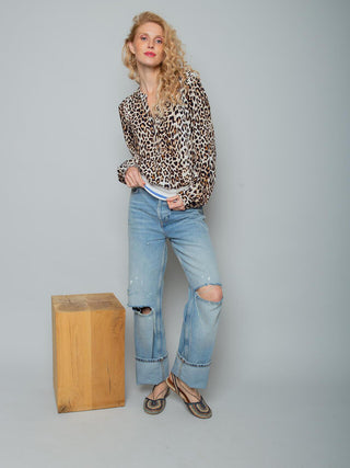 Emily Bluse 157500 leo: Frau in langärmeliger, leo-print Bluse von Emily van den Bergh, in helle Jeans gesteckt, mit flachen Sandalen. Bluse mit elastischem Strickbund und fließendem Stoff.