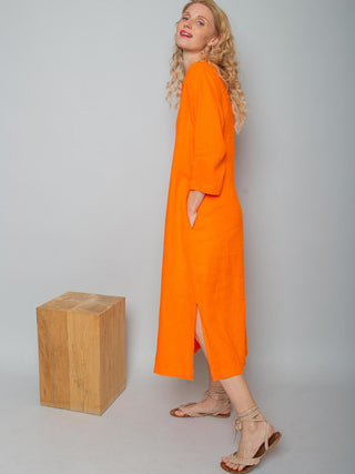 Das Emily Kleid 156770 orange zeigt ein lässiges, wadenlanges Leinenkleid mit V-Ausschnitt, Faltendetails, 3/4-Ärmeln und Seitenschlitzen, getragen von einem Model mit beigen Sandalen.