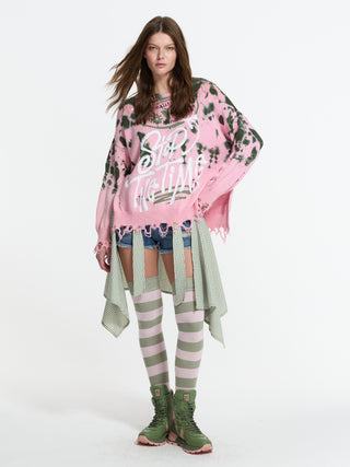 Modell trägt den #VDR Pulli 19158 khaki pink, einen oversized, zerschlissenen Strickpullover mit Schriftzug “STOP THE TIME”, kombiniert mit Jeansshorts und gestreiften Overknee-Strümpfen.