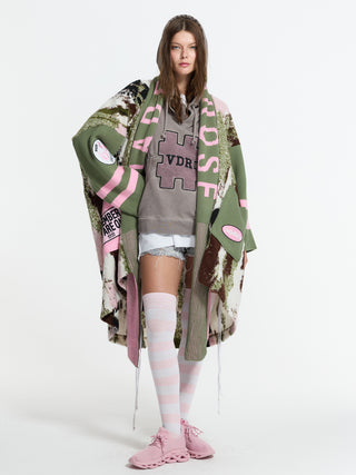 #VDR Cardigan 19207 khaki: Patchwork-Cardigan im Oversize-Look mit grafischen Buchstaben auf Ärmeln, kombiniert mit lässigem Layering-Stil über einem Hoodie, kurzen Denim-Shorts und trendigen, pinken Sneakers.