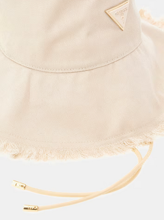 Nahaufnahme des GUESS Sally Hat BEI, einem hellbeigen Baumwoll-Bucket-Hut mit leicht ausgefranstem Rand, verstellbaren Kinnriemen mit Metallenden und einem kleinen dreieckigen Metalllogo an der Seite.