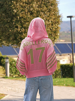 Person von hinten auf einem Weg, trägt #VDR Pulli 19165 pink khaki: grob gestrickte Kapuzenjacke mit olivegrüner 17 und Streifen, kombiniert mit weitem Schnitt und entspanntem Stil.