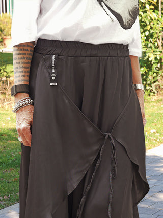 Person trägt den #VDR Skirt 19231 black mit Kordeldetail, locker gebunden für eine asymmetrische Silhouette, kombiniert mit einem weißen T-Shirt. Der Rock zeigt eine fließende Bewegung.