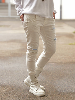 OFF#DLY Denim Turin white: Schmale, leicht figurbetonte off-white Jeans mit dezenten Destroyed-Details an Oberschenkeln und Knien. Kombiniert mit weißen High-Top-Stiefeln, ideal für vielseitige, stilvolle Looks.