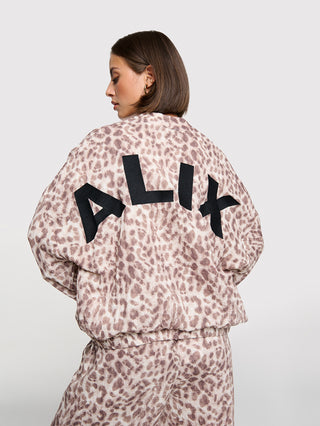 Person von hinten in einem ALIX Sporty Animal Jaclet, einem leicht gekürzten, oversized Leoparden-Jacke mit schwarzem ALIX-Logo. Kombiniert mit passenden, lässig geschnittenen Leopardenhosen.