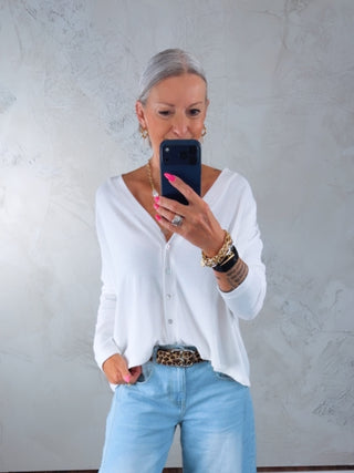 Person in Spiegel-Selfie trägt den Cotton Candy Cardigan Ori white, ein weißes, locker sitzendes Knopf-Front-Top, kombiniert mit hellen Jeans, Leoparden-Gürtel und goldenen Schmuck.