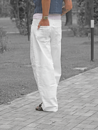 Person trägt OFF#DLY Wide Leg Denim Gina white mit weitem Bein und hohem Bund. Die weiße Hose kombiniert mit schwarzen Sandalen und Accessoires, betont durch den lässigen, modernen Fall.