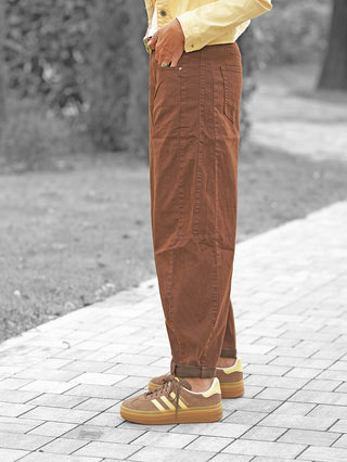 Tragende Person zeigt die OFF#DLY Barrel Color Denim Mia brown mit aktuellem Barrel-Fit, lockerem Schnitt, leichtem Stretchanteil, kombiniert mit braunen Adidas Gazelle Sneakers und einem gelben Jackenabschluss.