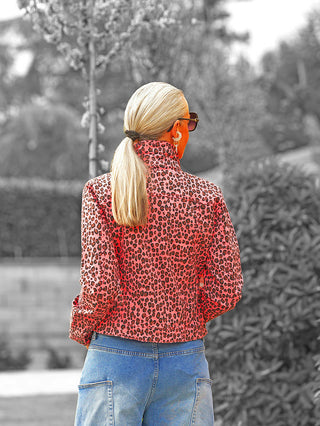 Rückansicht der OFF#DLY Jacke Aice Leo Pink mit auffälligem Leoparden-Print und hochgestelltem Kragen, getragen von einer Frau mit blonden Haaren im Zopf, kombiniert mit blauer Jeans.