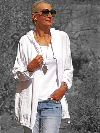 Frau in der OFF#DLY Jacke Samira weiß, locker über einem Tanktop getragen, kombiniert mit Jeans. Die Jacke zeigt ein dekoratives Flügel-Design und verleiht dem Outfit eine lässige Eleganz.