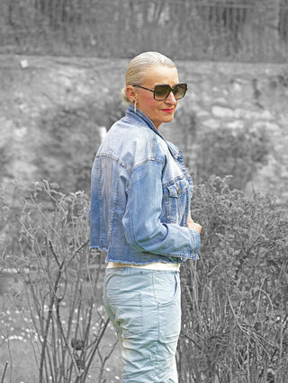 Person im Profil mit blonden Haaren, trägt die OFF#DLY Jacke Sanna midblue, eine kurze, lässige Denim-Jacke mit markanten Nähten und Knopfleiste, kombiniert mit passenden Jeans.