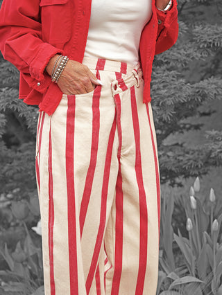 Die Lumina Hose Davina beige/rot zeigt sich mit hohen Bund, weiten Beinen und markanten roten Streifen. Kombiniert mit weißem Top, roter Jacke und Silberarmreifen, bietet sie italienisches Flair.