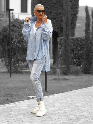 Frau trägt die OFF#DLY Denim Bluse Pia lightblue mit Herzmuster, über weißem Top, kombiniert mit hellen Skinny Jeans und Sneakers, im lässigen Stil.
